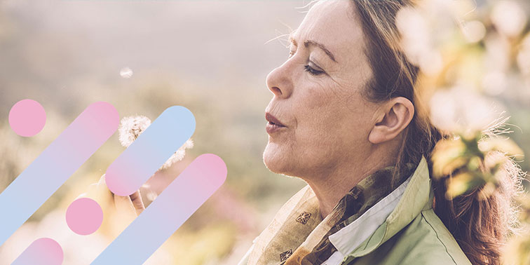 A woman blows the seeds off a dandelion