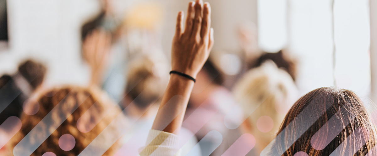 A person raises their hand in a crowded room